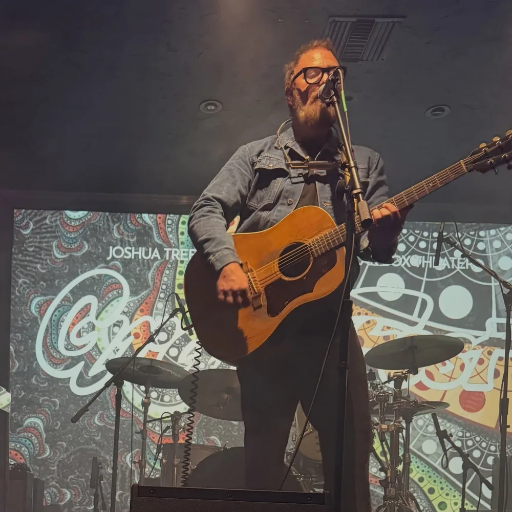 Brad Byrd singing with an acoustic guitar on stage at Gramfest in Joshua Tree