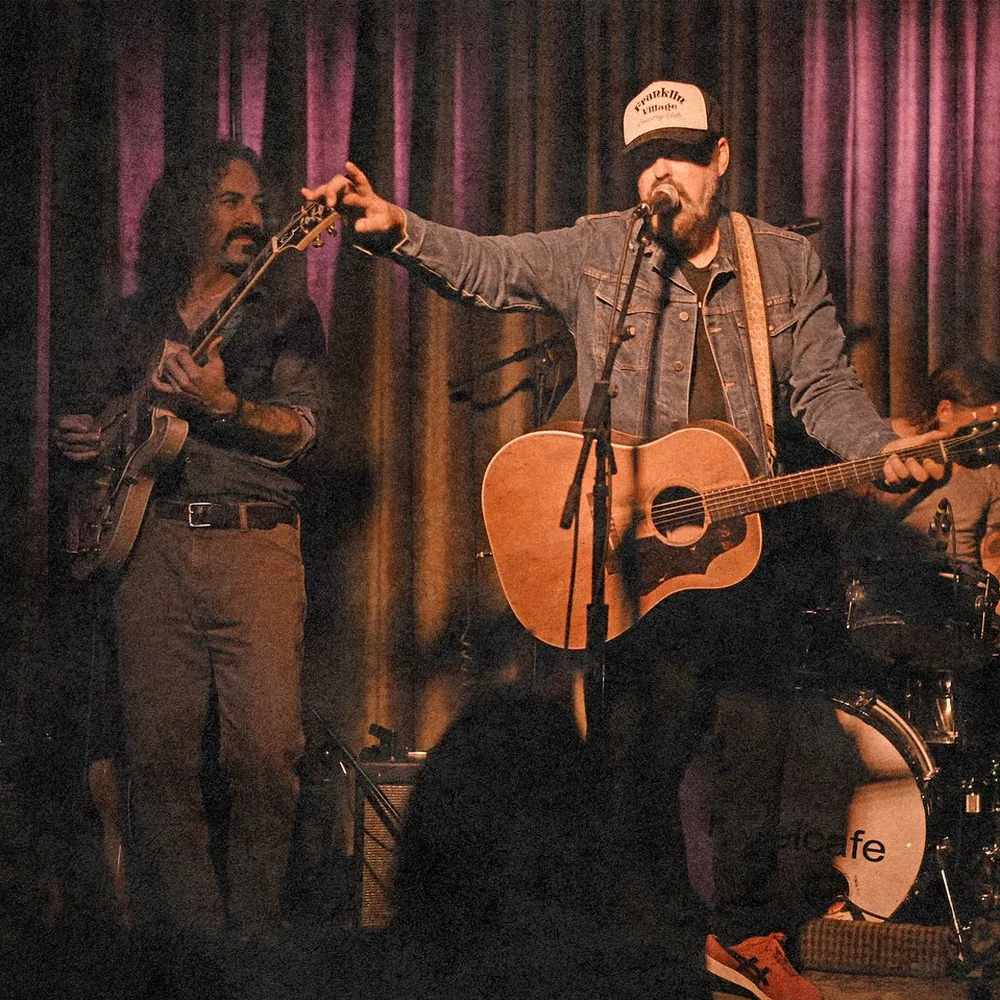 Brad Byrd singing with his acoustic guitar and band on the Hotel Cafe stage in Hollywood